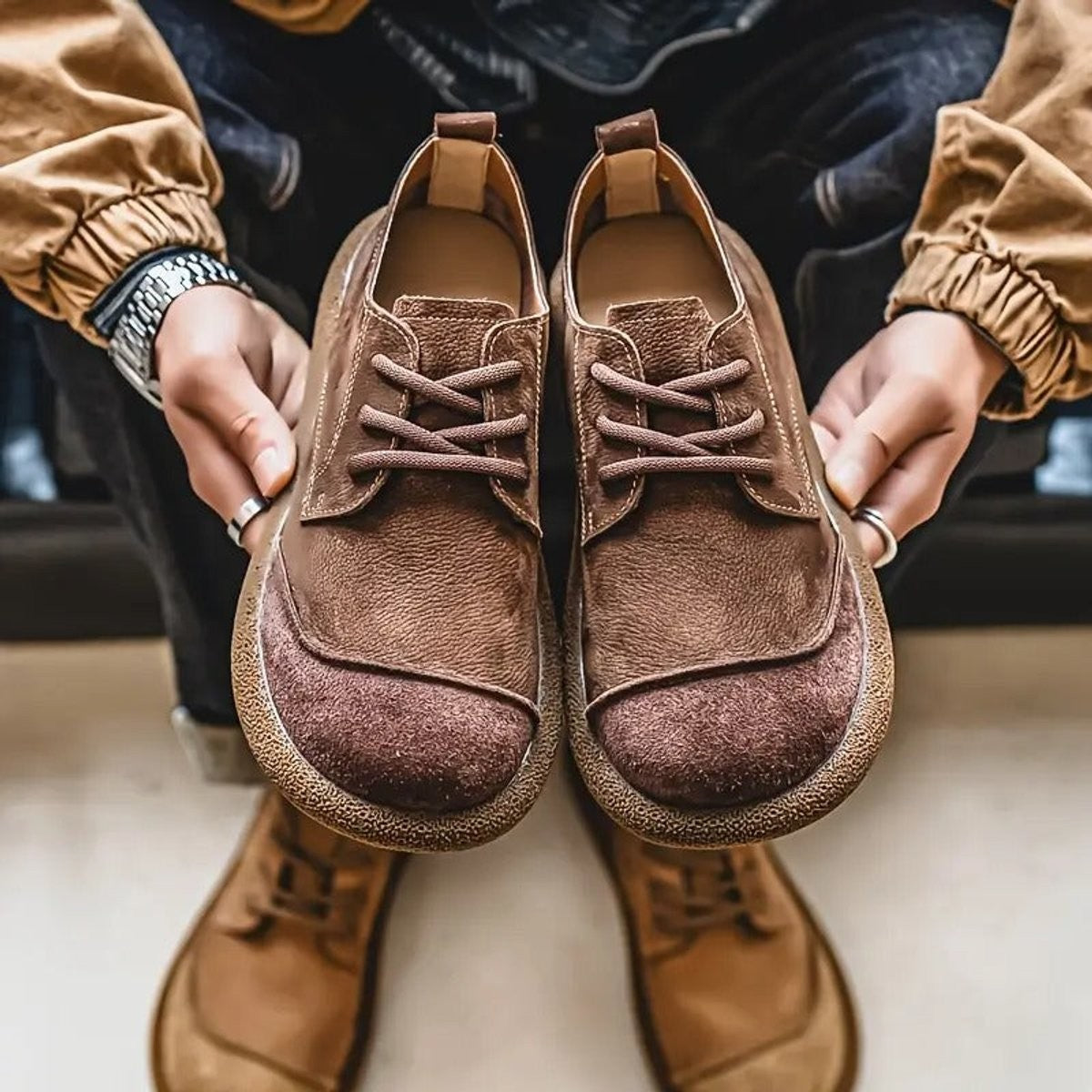 Chocolate leather trainers held in hand showing padded interior