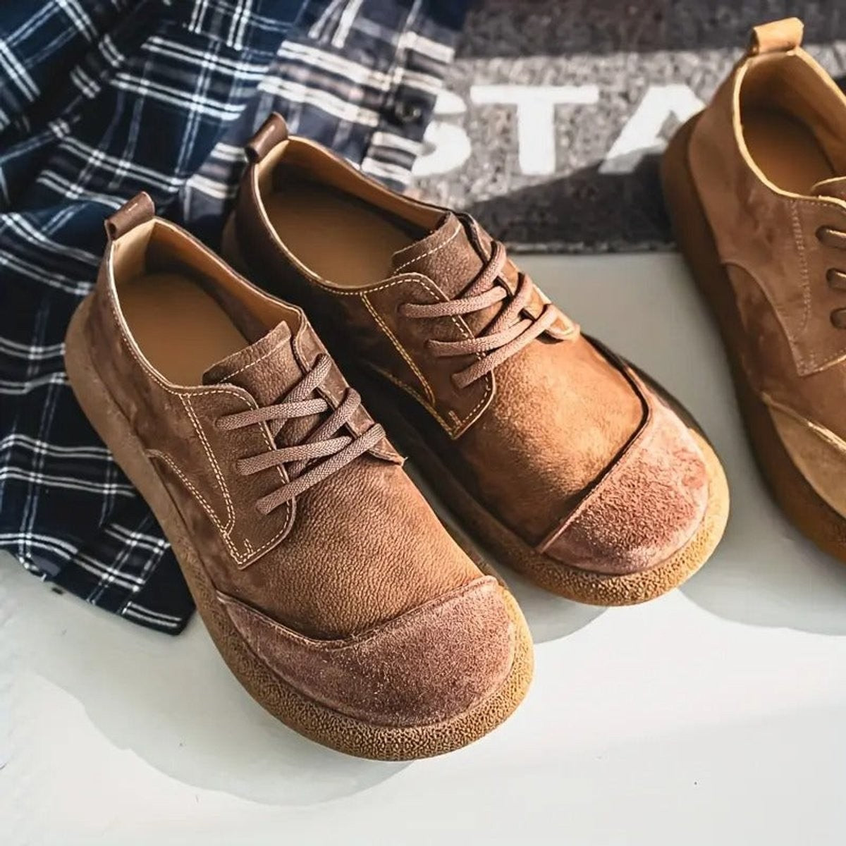 Deep brown suede-toe leather shoes against striped shutter backdrop