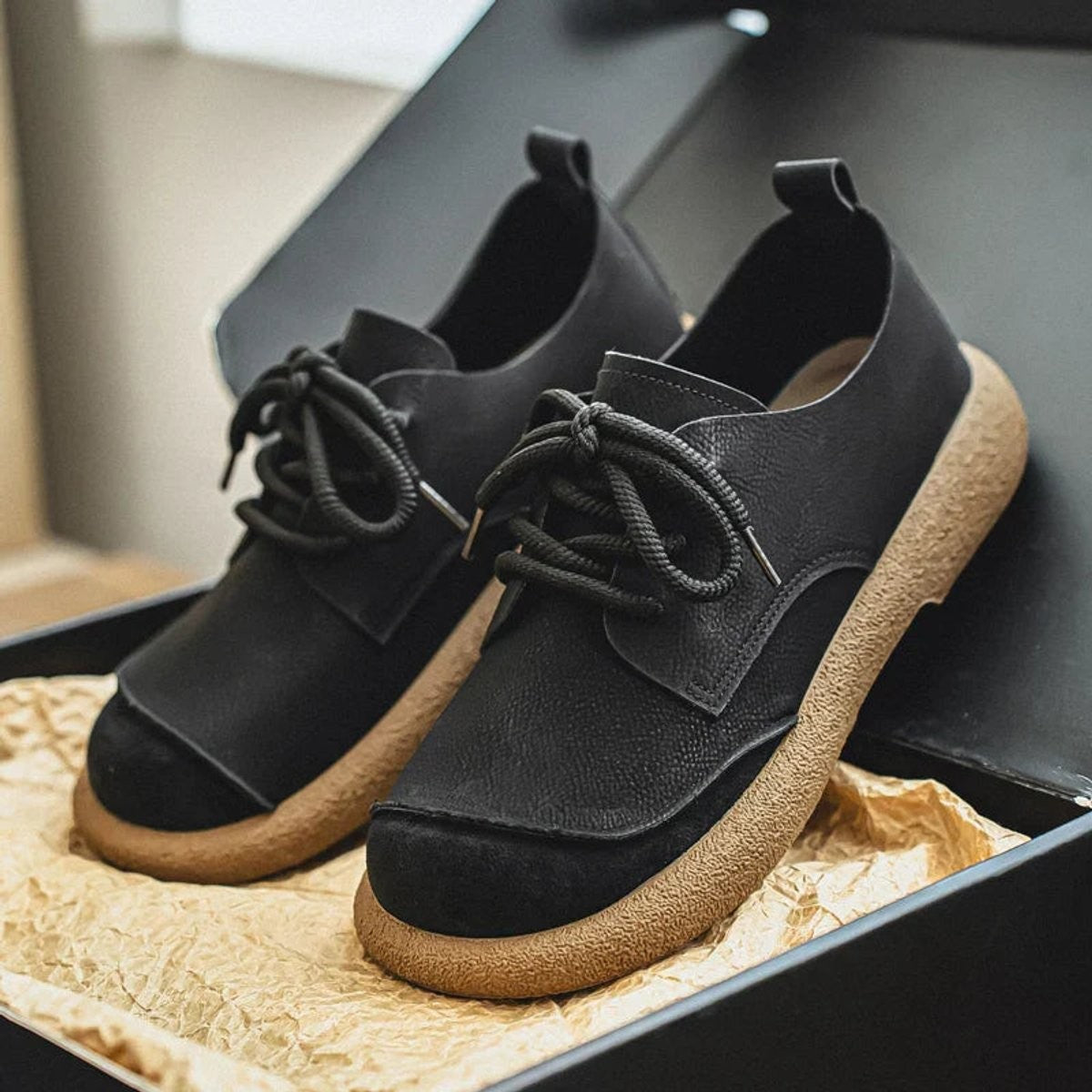 Tan leather trainers with pink-toned suede toe held on car dashboard