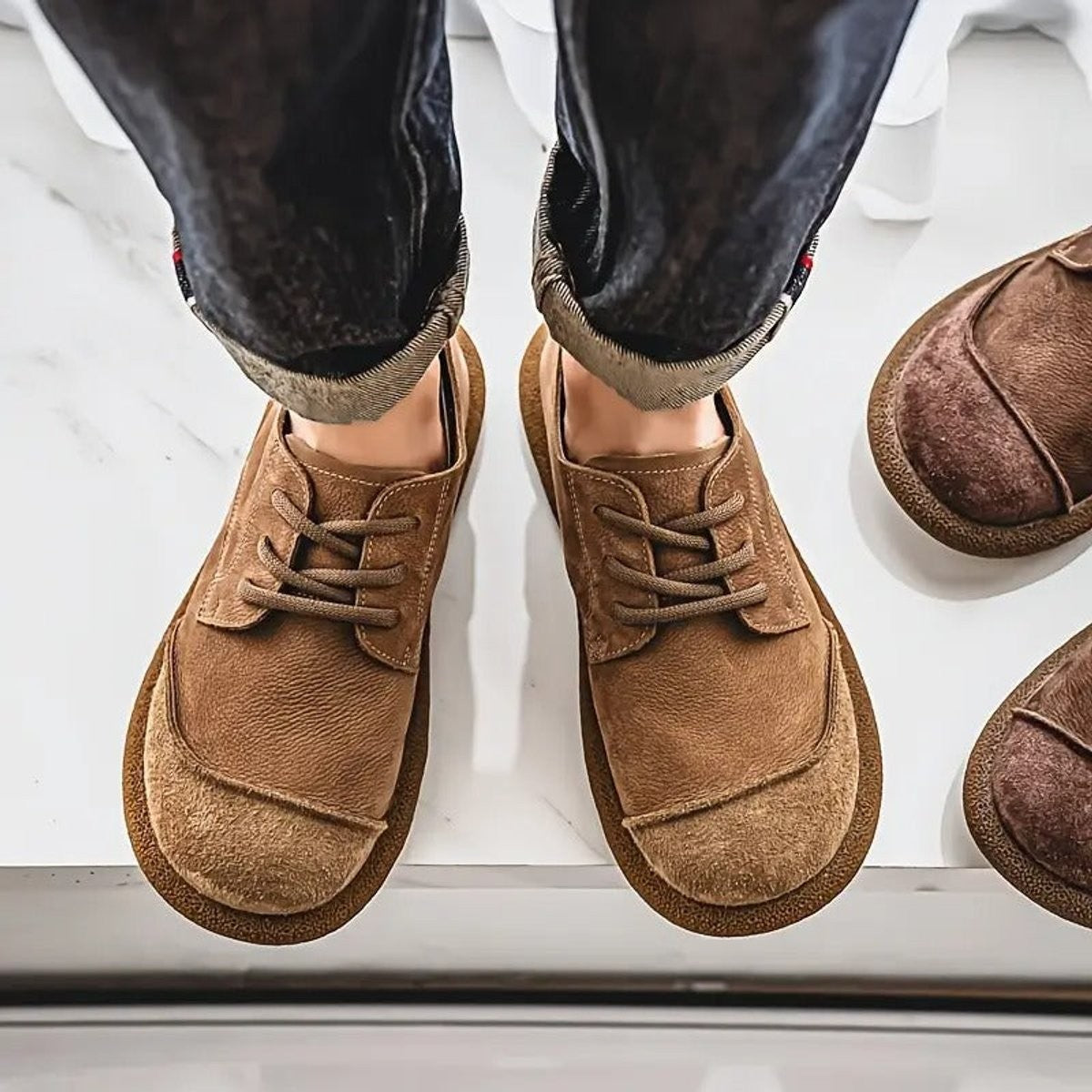 Brown leather trainers worn with rolled-up jeans and suede toe
