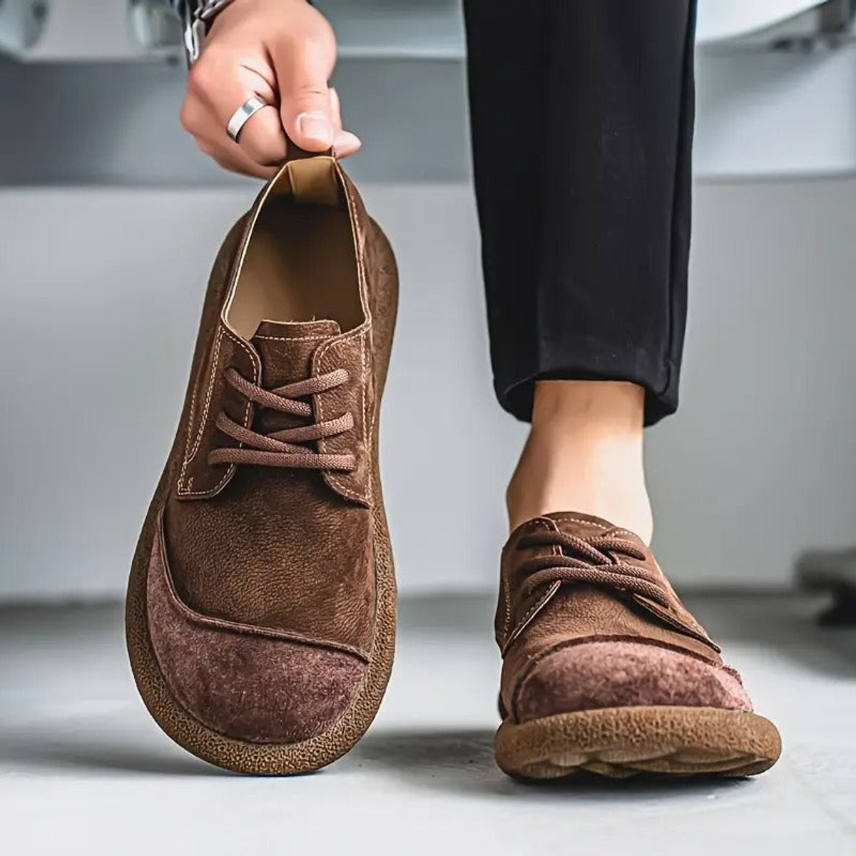 Chocolate brown leather trainers worn with tapered black trousers