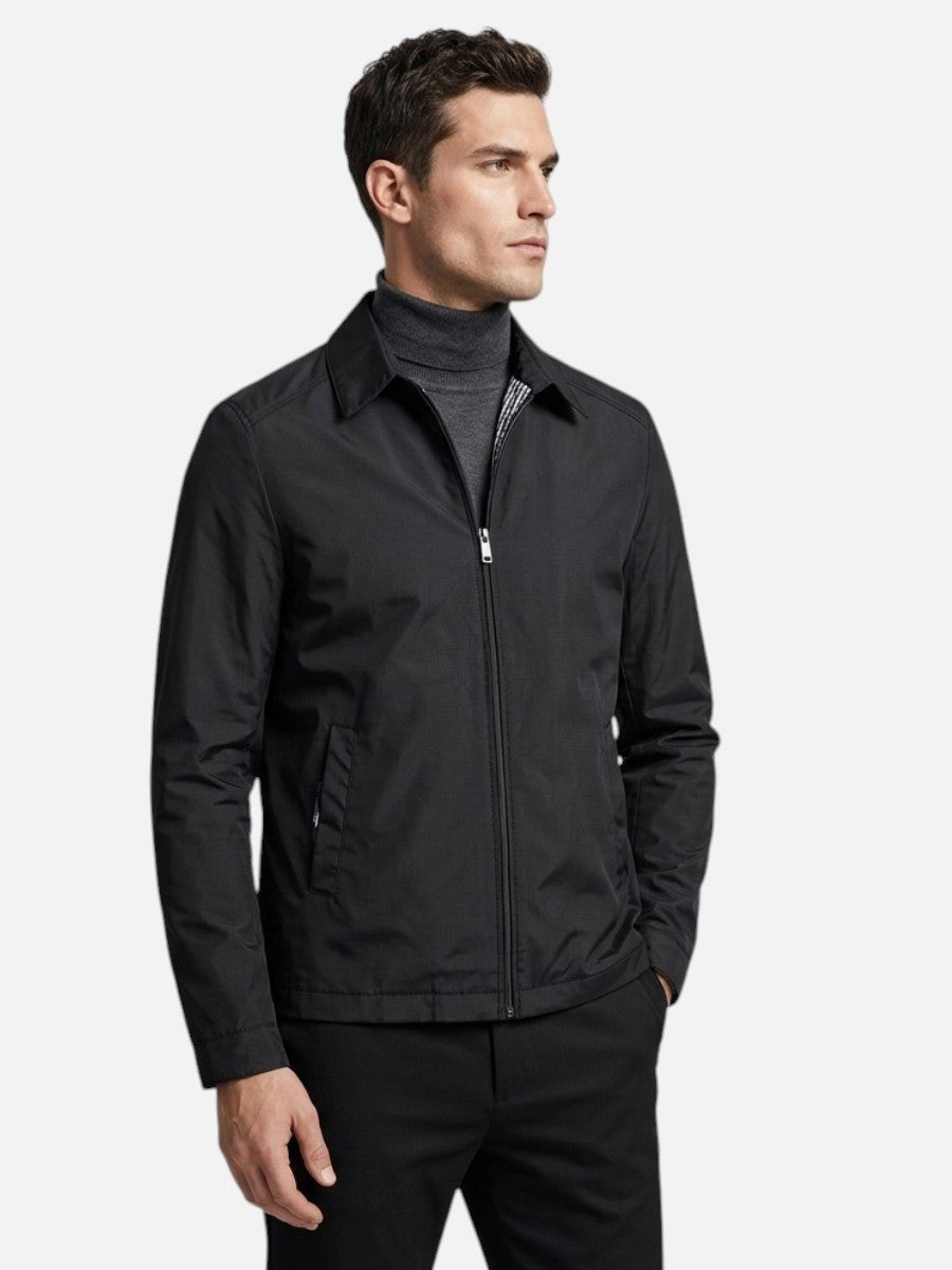 Man wearing black zip-up bomber jacket over grey polo neck jumper
