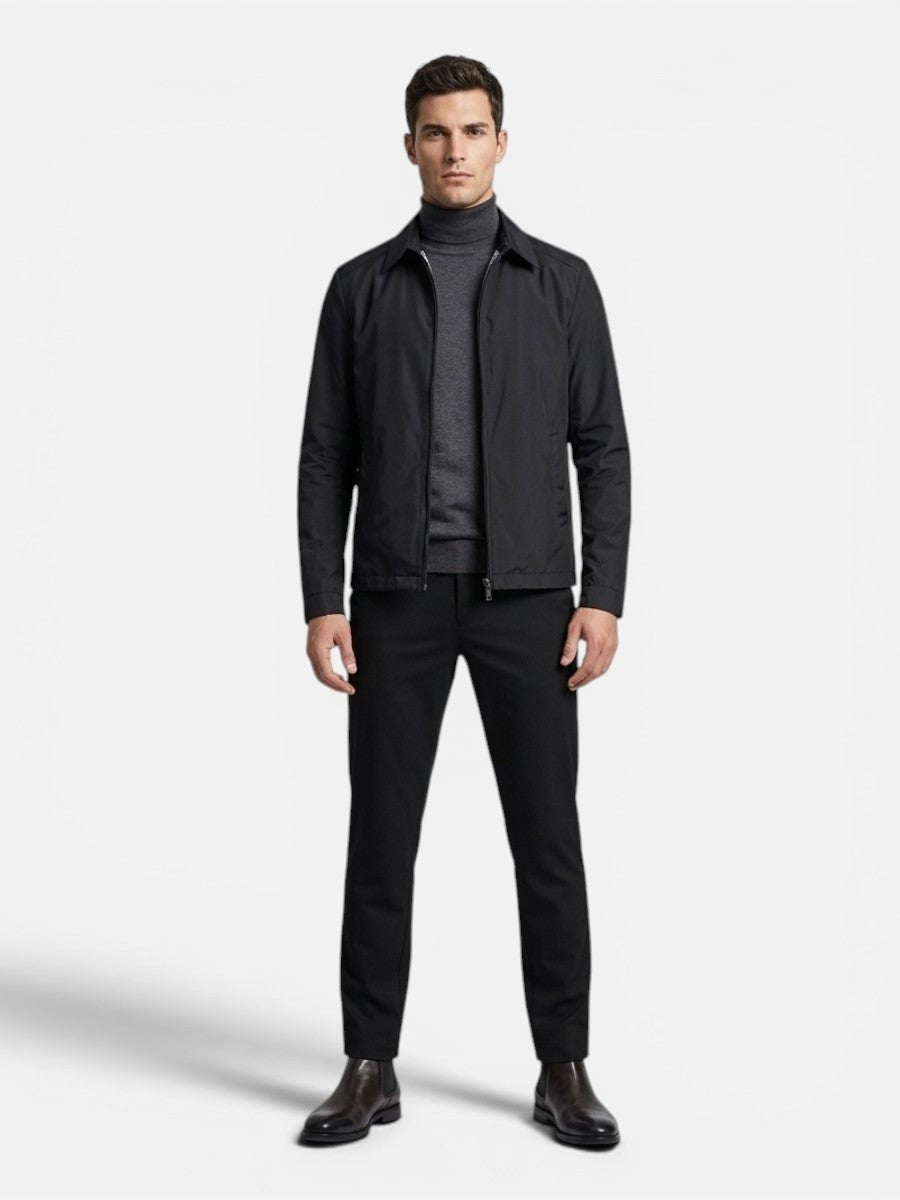 Full-length view of man styling black bomber jacket with tailored trousers