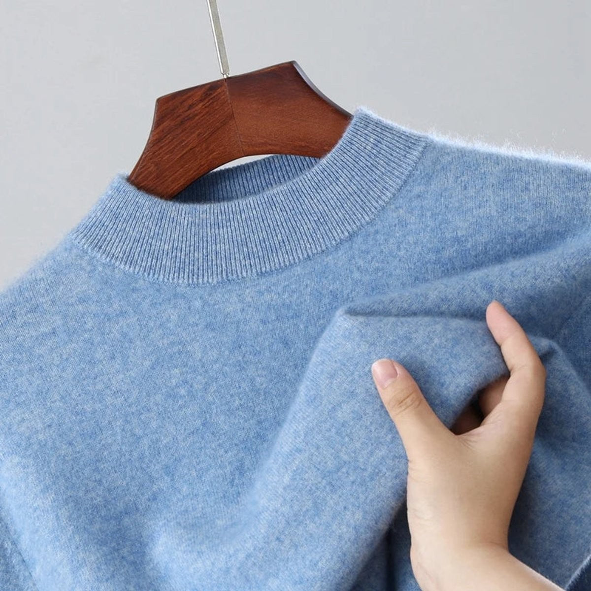 Close-up of pale blue mock-neck jumper on hanger showing ribbed collar and soft knit