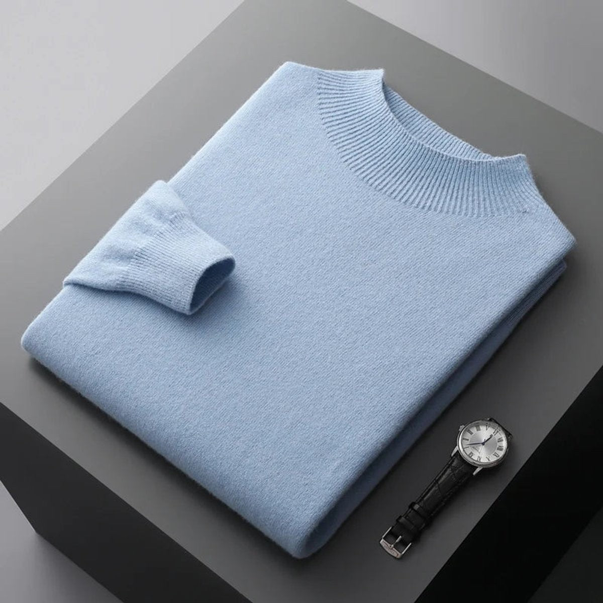 Pale blue cashmere blend jumper folded neatly beside a leather-strap wristwatch