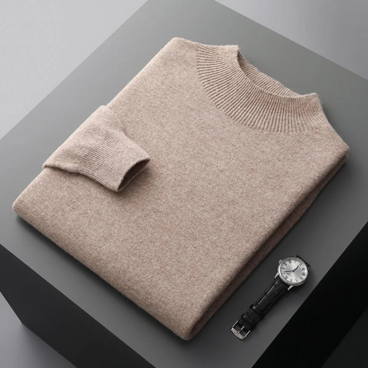 Beige cashmere blend jumper folded with ribbed collar shown beside a wristwatch
