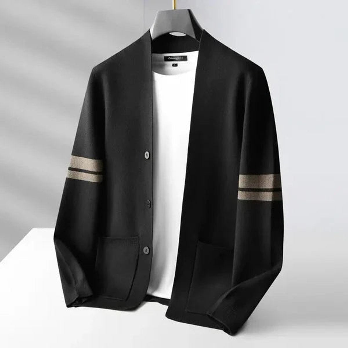 Black merino wool blend cardigan with beige striped sleeves on hanger