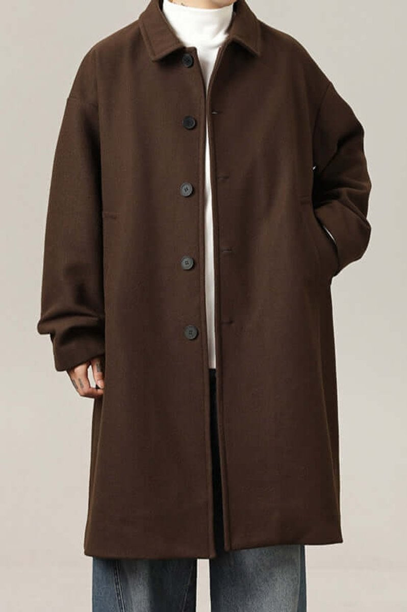 Brown oversized longline coat with buttoned collar, worn with white polo neck