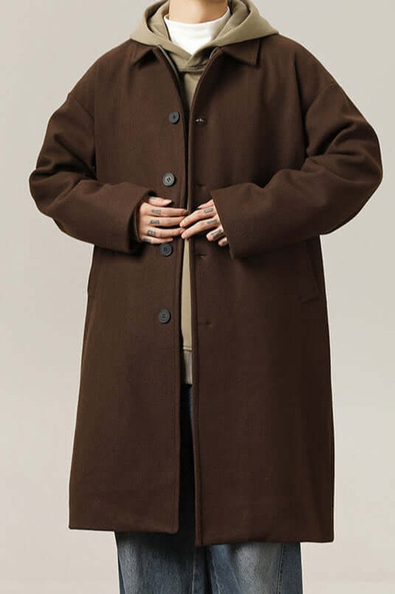 Model buttoning up brown oversized wool-look coat over khaki hoodie