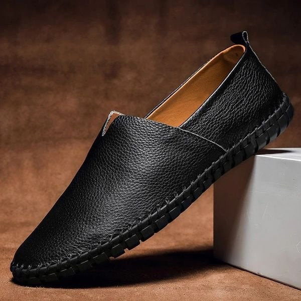 Black pebbled-grain leather loafers showing whipstitched sole and slip-on finish