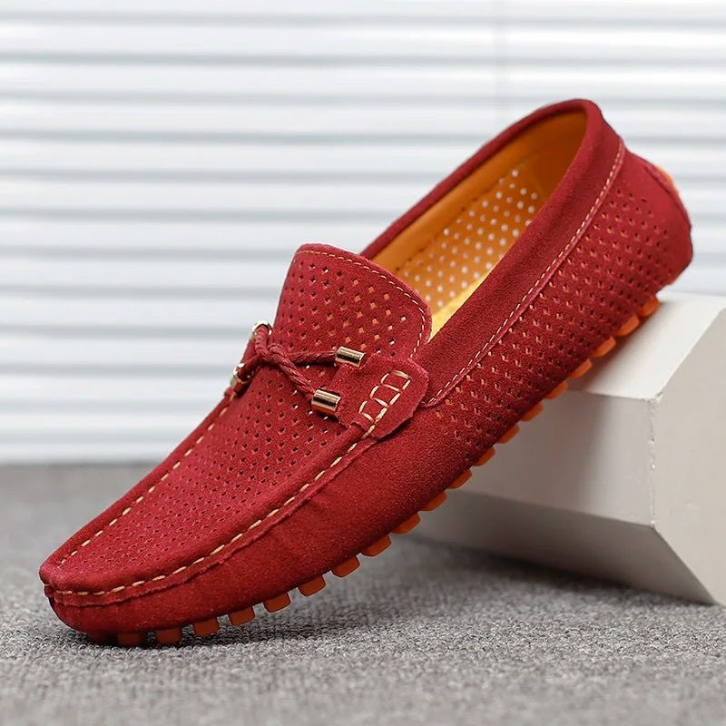 Wine red suede perforated loafers displayed against a striped background
