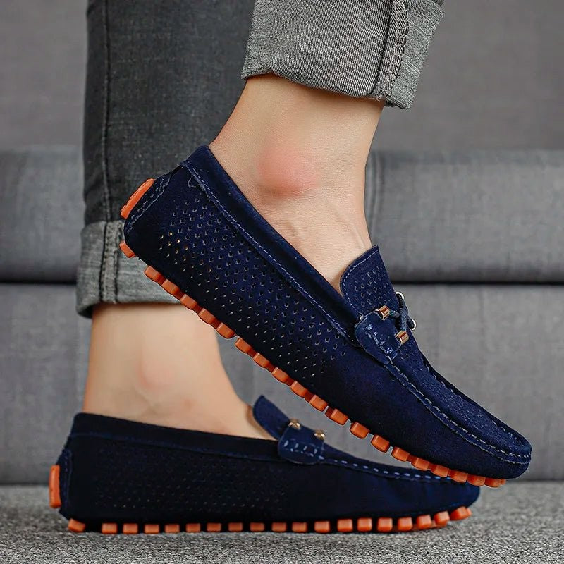 Navy suede perforated loafers worn with grey turned-up trousers, side view