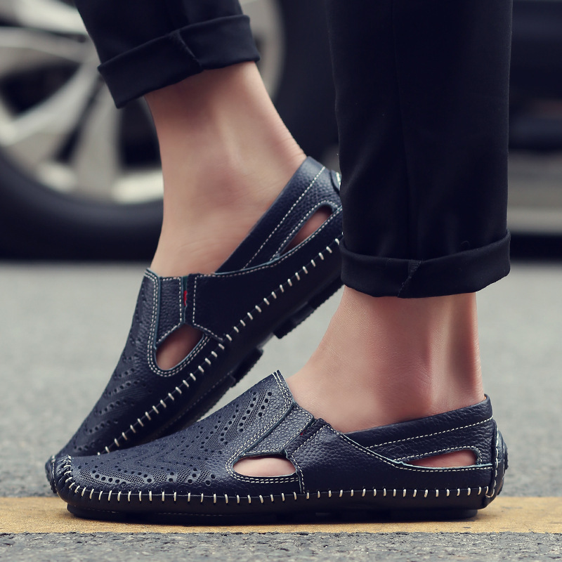 Navy perforated leather sandals worn on foot with rolled black trousers