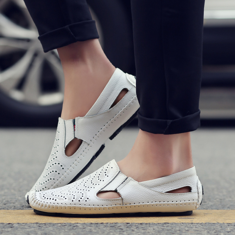 White perforated leather sandals worn on foot with rolled-up black trousers