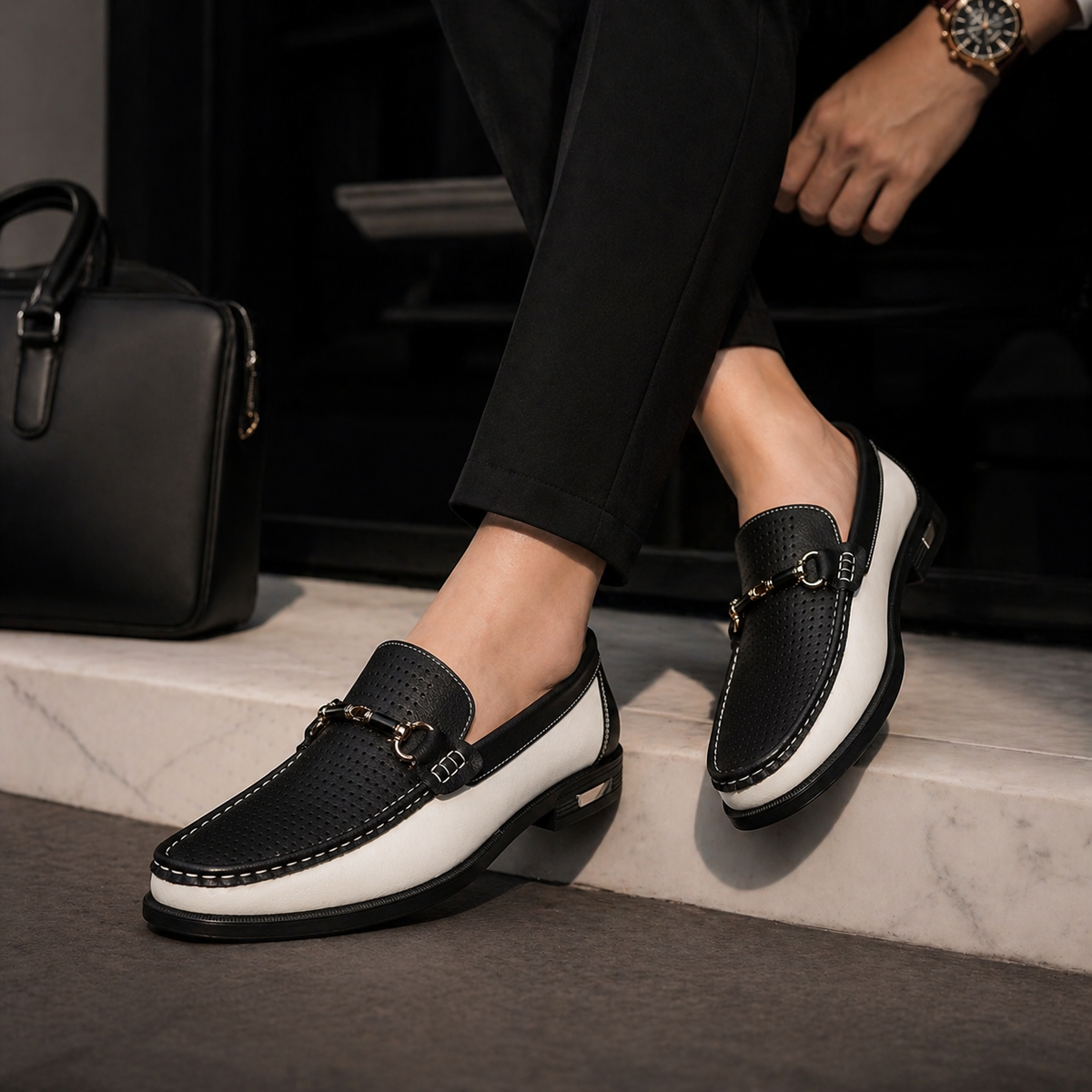 Black and white leather loafers worn with cropped black trousers on steps