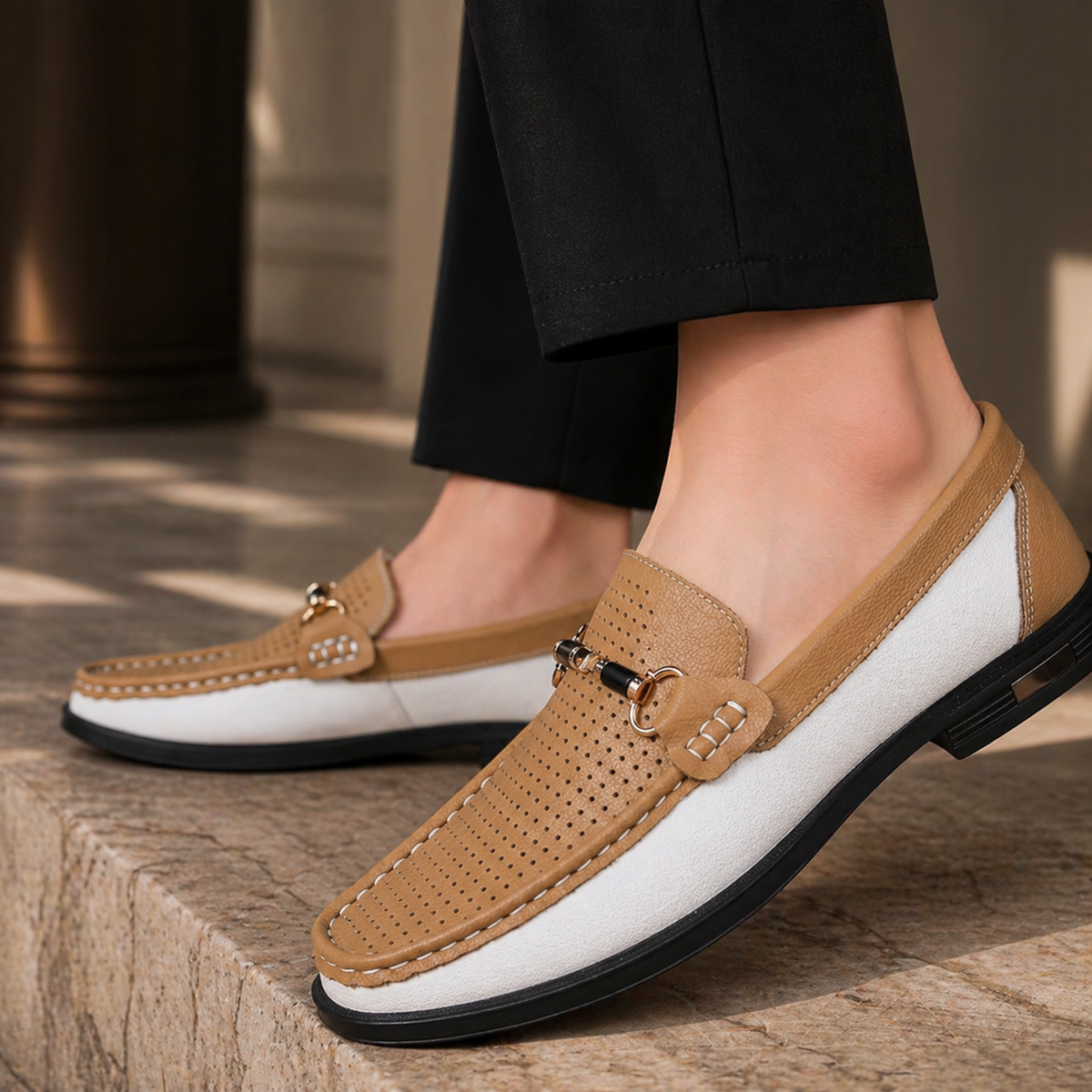 Tan and white perforated leather loafers worn with black tailored trousers