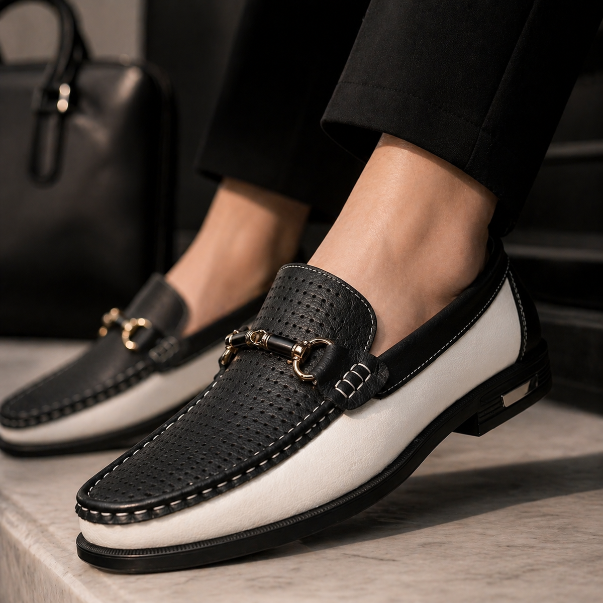 Black and white loafers worn on foot, showing perforated leather detailing