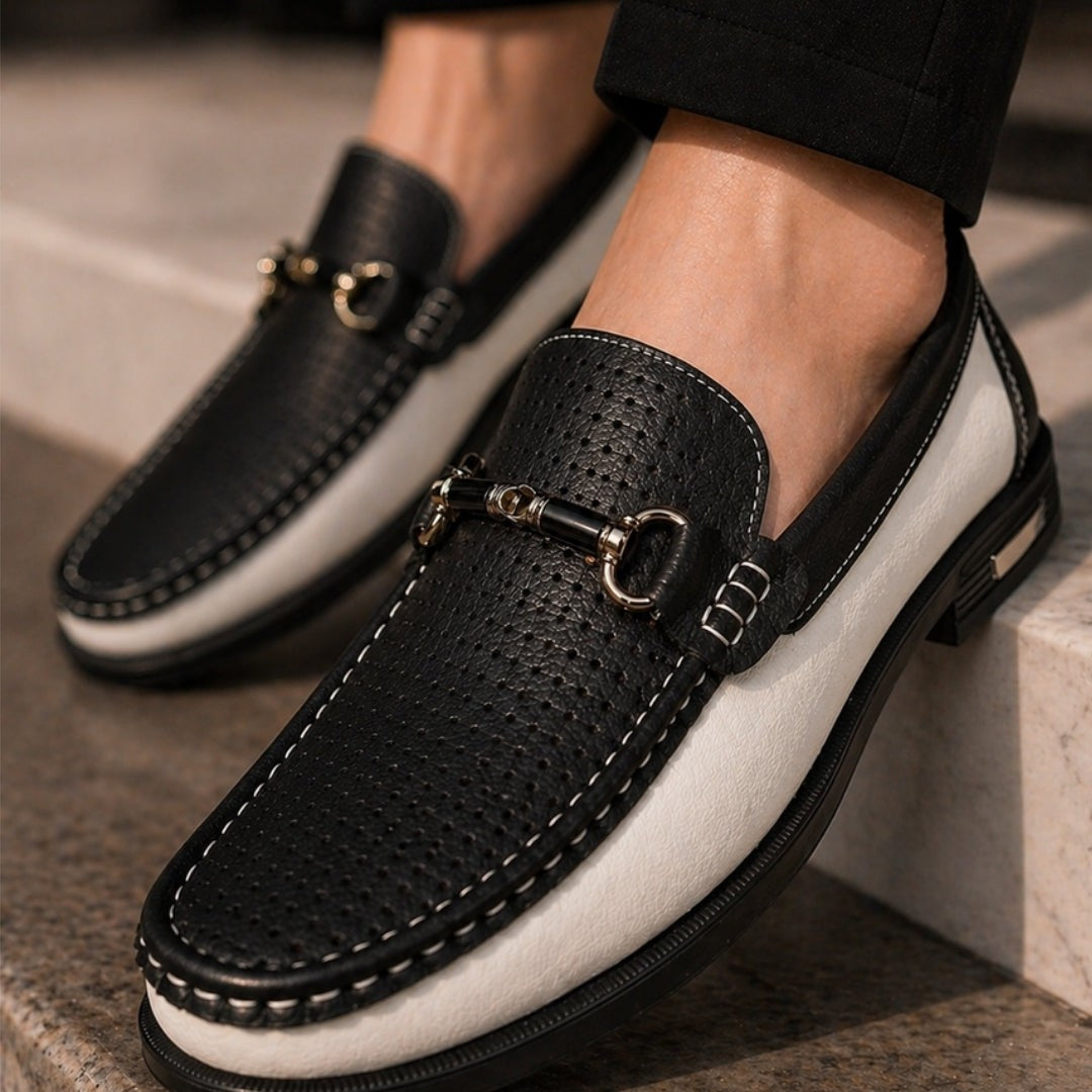 Close-up of black and white perforated loafers with gold hardware trim