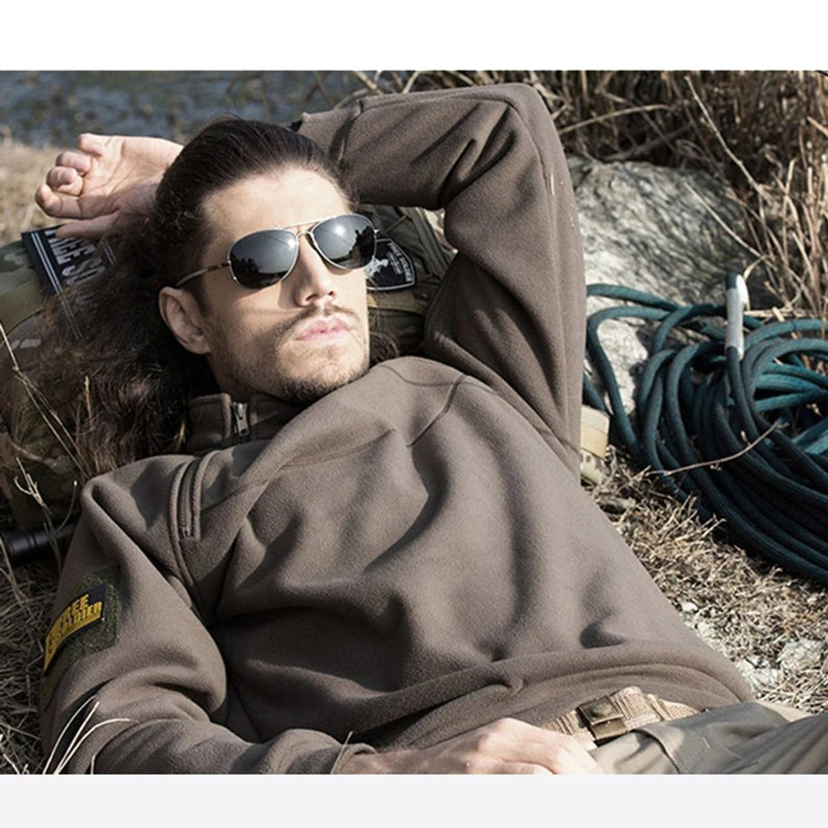 Man wearing brown fleece quarter-zip jumper relaxing outdoors in tactical style