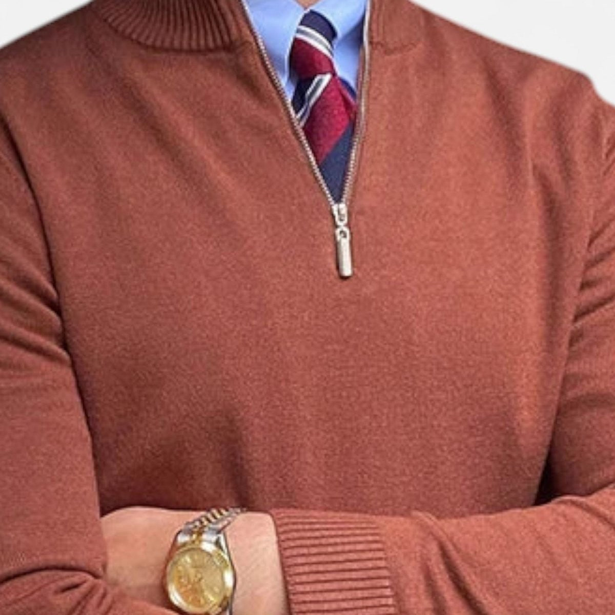 Rust-coloured half-zip knitted jumper layered over blue shirt and tie