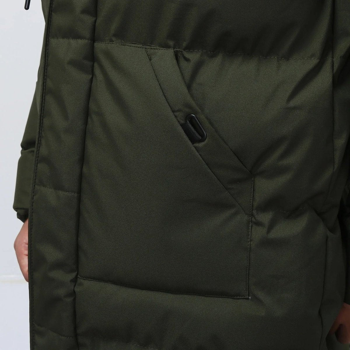 Close-up of khaki puffer coat side pocket with toggle fastening