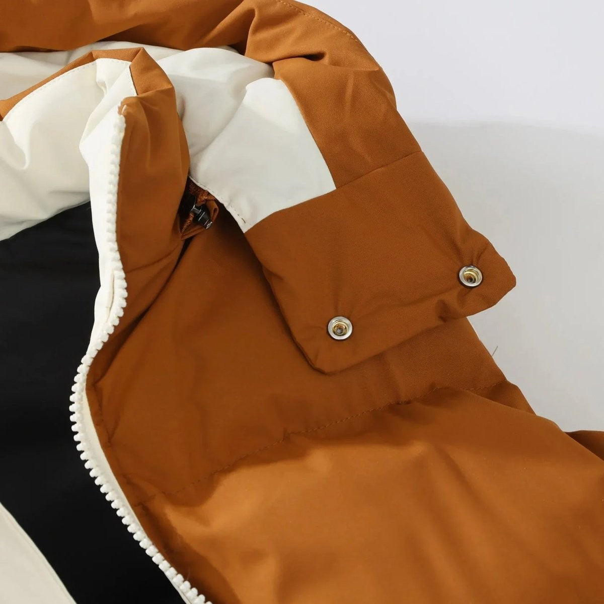 Detail shot of tan puffer vest cuff with popper fastening