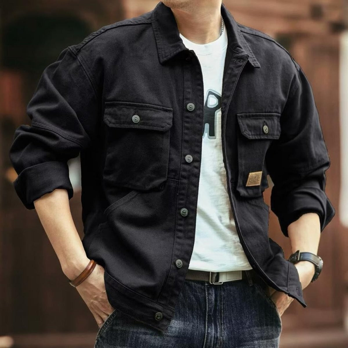 Black cotton canvas utility jacket featuring twin flap pockets and studded buttons