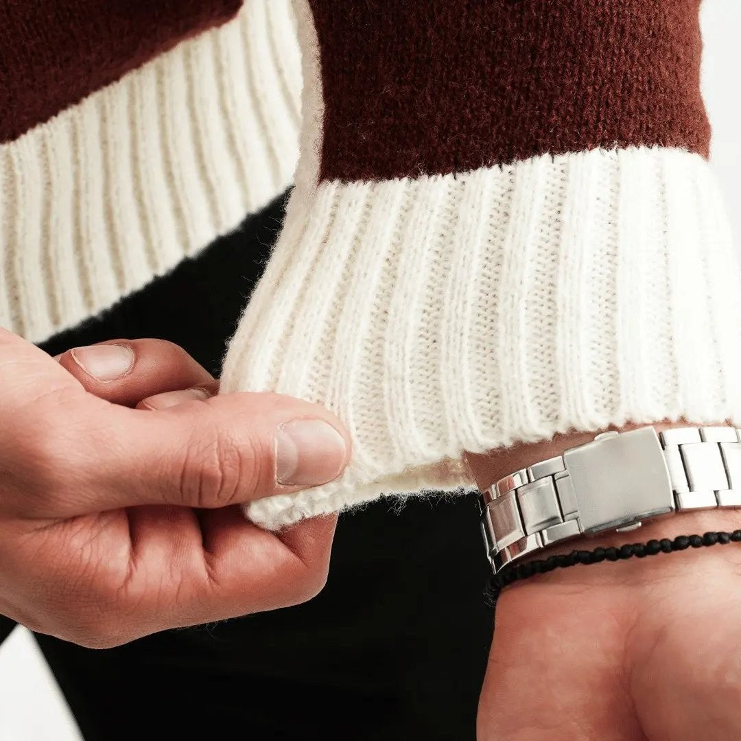 Close-up of ribbed cuff detail on burgundy and cream knit jumper sleeve