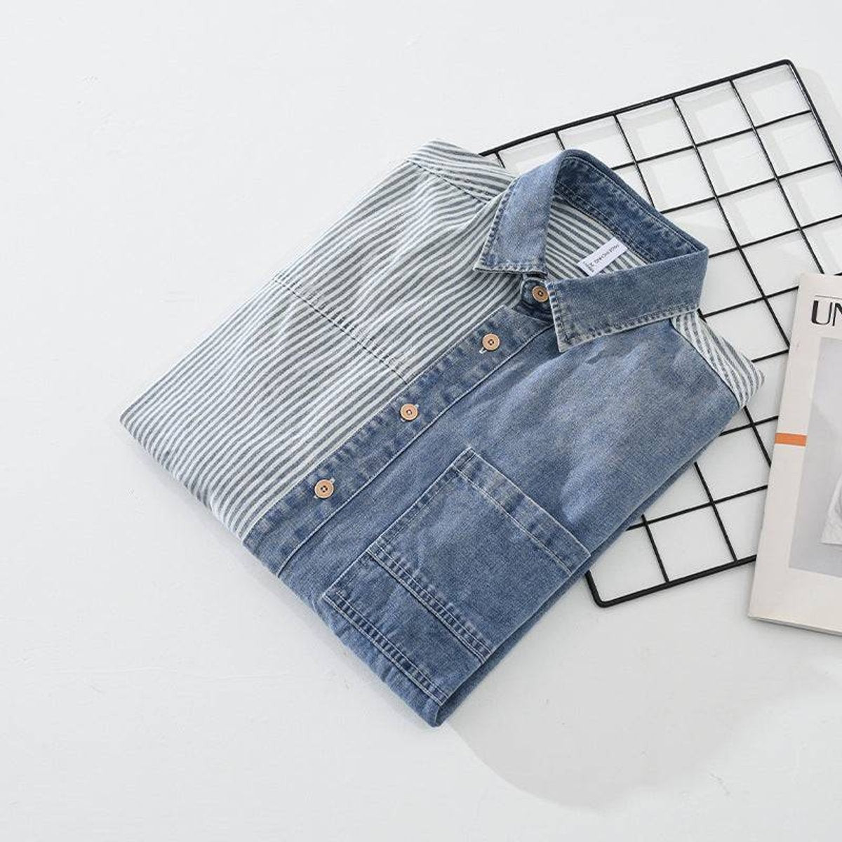Folded striped denim shirt showing button placket and patch pocket