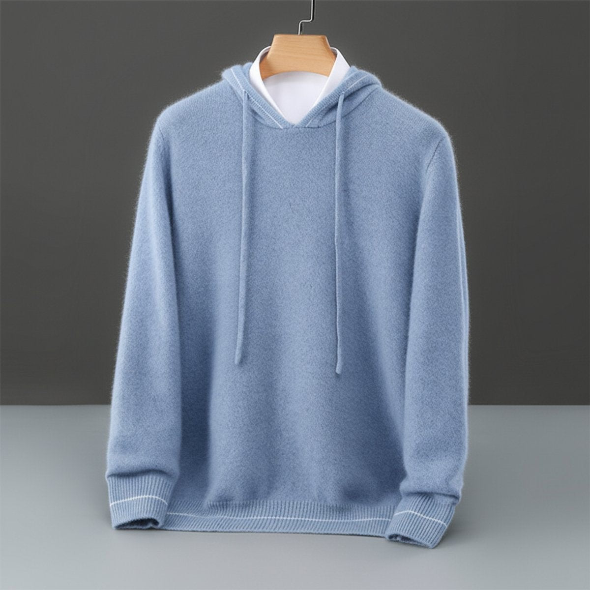 Powder blue cashmere hooded jumper with drawstring hood, hung on wooden hanger