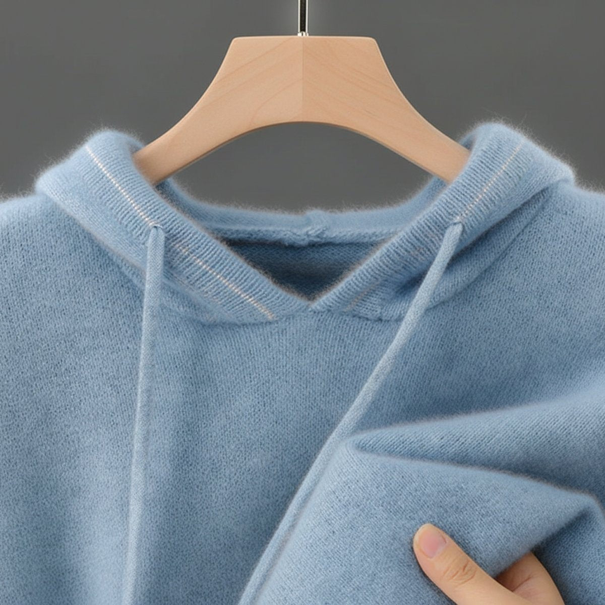 Close-up of pale blue cashmere hoodie showing ribbed trim and soft knit texture