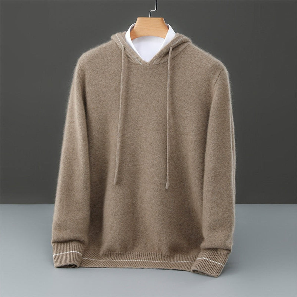 Camel cashmere hoodie with drawstring hood and ribbed hem, displayed on hanger