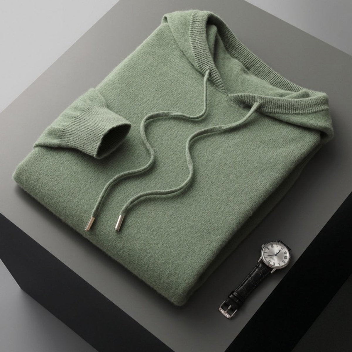 Folded sage green knitted hoodie jumper with drawstring and ribbed hem