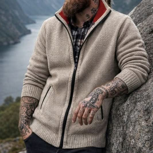 Man wearing beige zip-up knit cardigan with red-trimmed collar outdoors