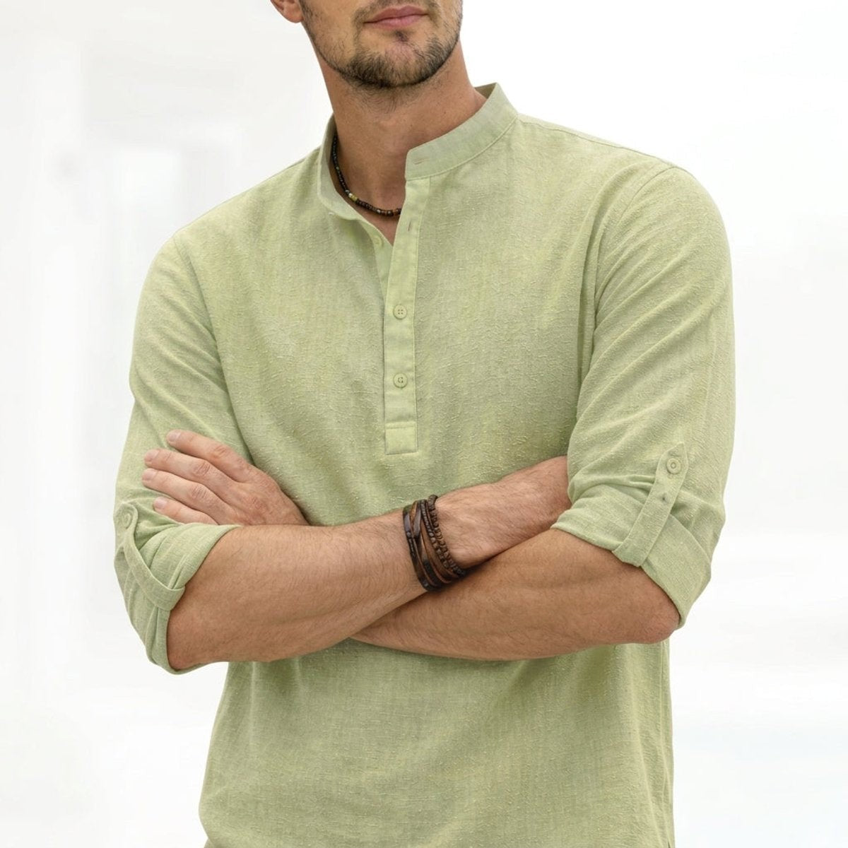 Sage green linen henley shirt with grandad collar, folded-arm pose