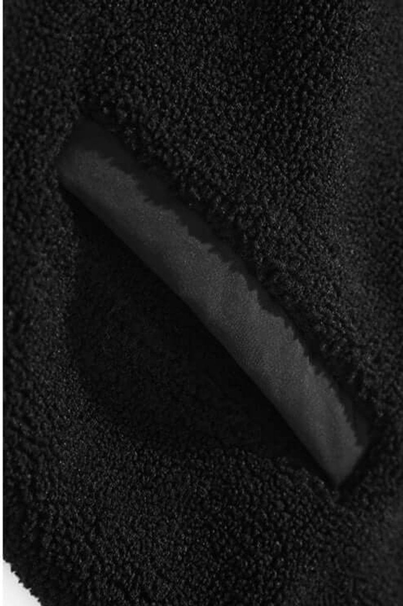 Textured close-up of black sherpa fleece fabric with contrast lining