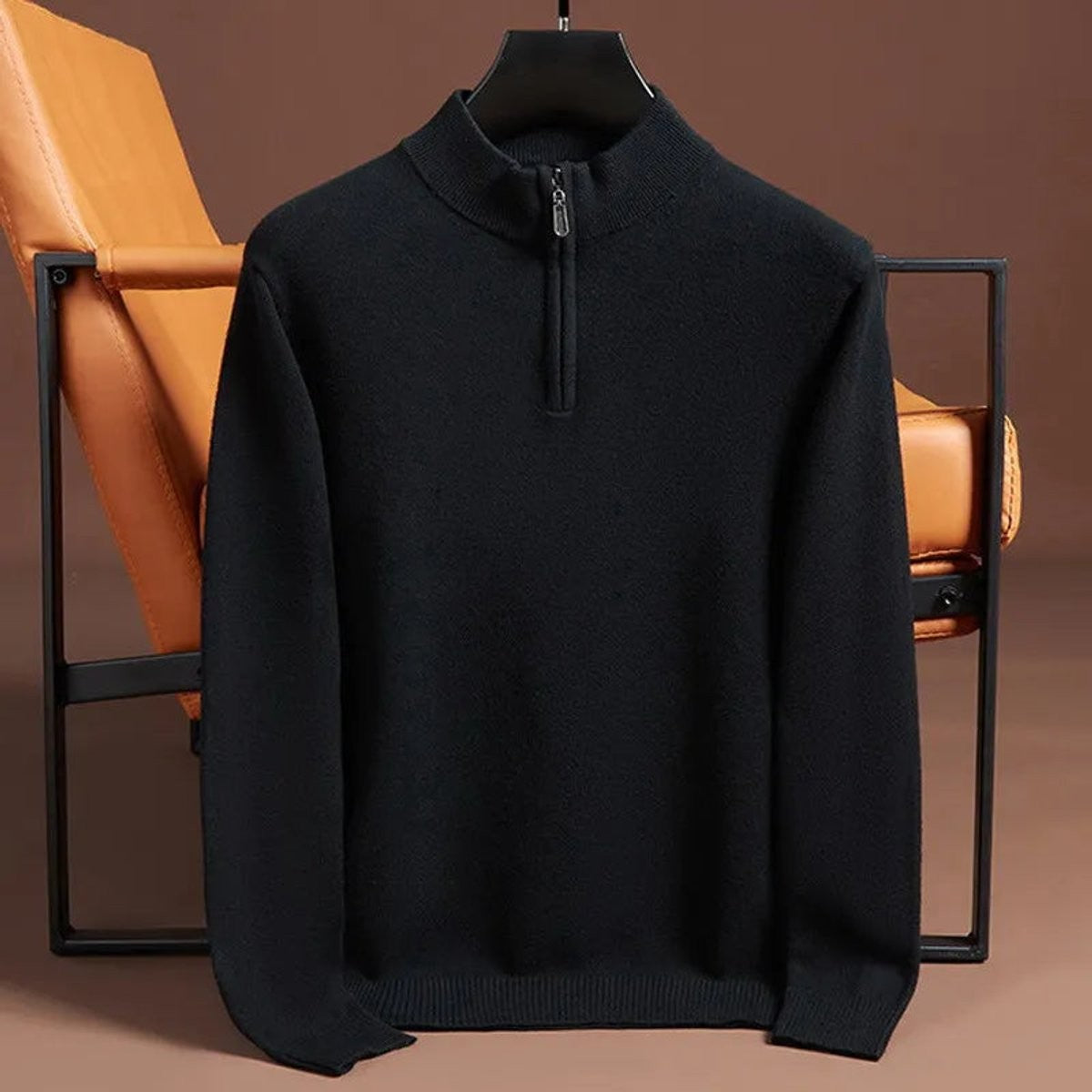 Black quarter-zip knitted jumper hanging against leather chair