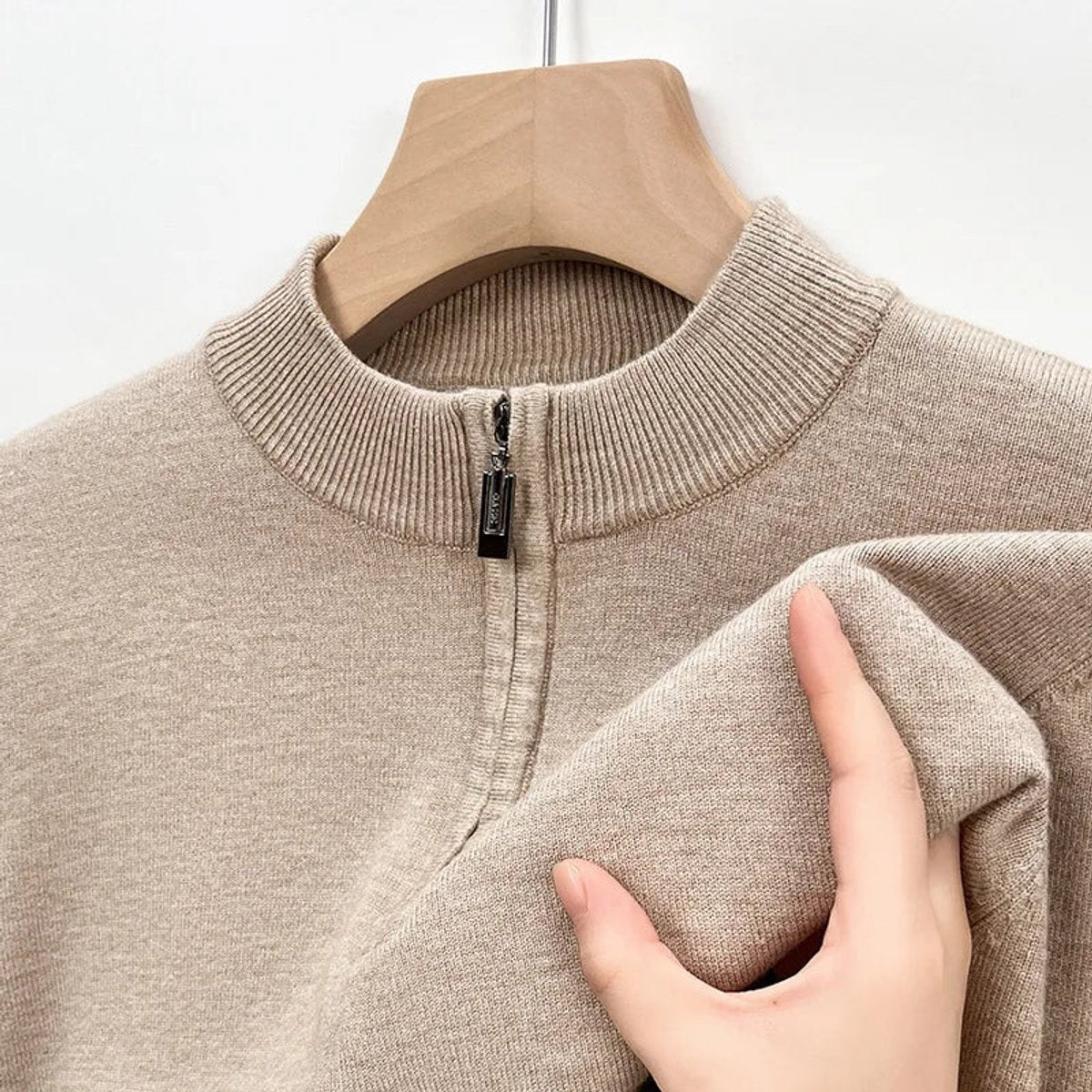 Close-up of beige knitted jumper collar showing zip pull and ribbed texture