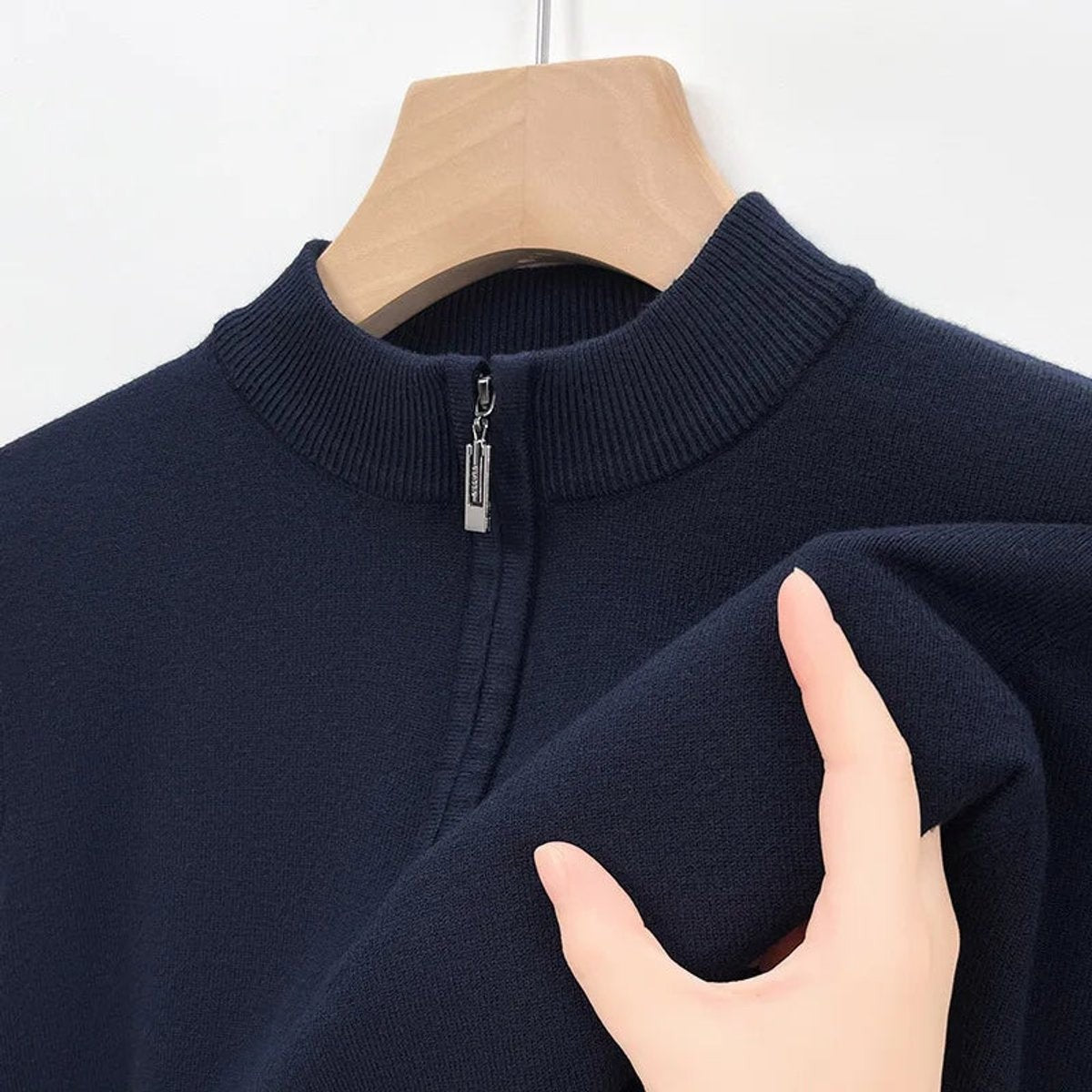 Navy quarter-zip jumper collar shown with hand touching soft knit fabric