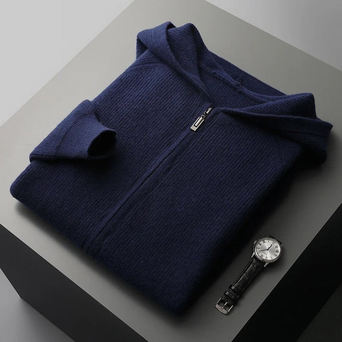 Folded navy cashmere blend zip hoodie jumper styled beside a wristwatch