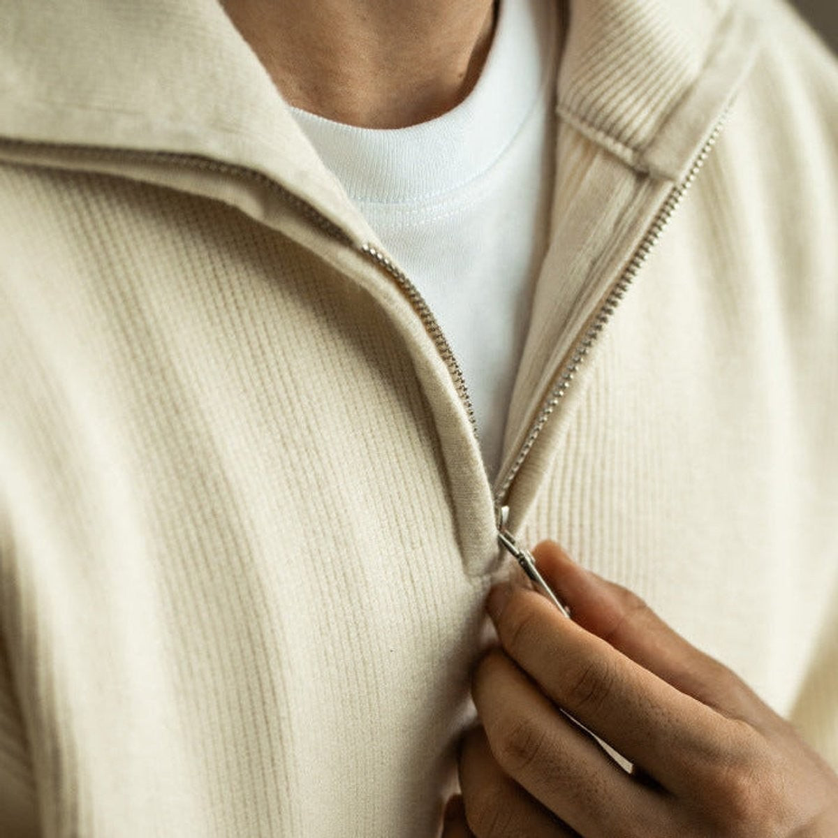 Close-up of cream ribbed knit jumper collar and zip pull