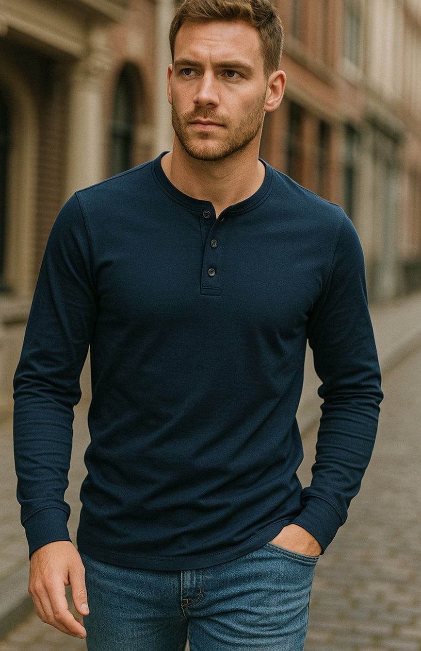 Man wearing navy henley shirt with jeans in an urban street setting