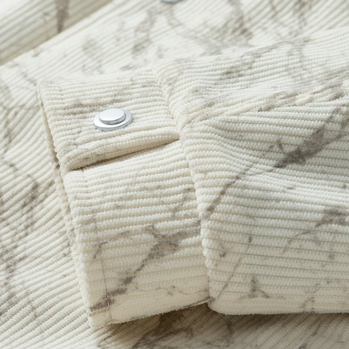 Close-up of popper cuff fastening on cream corduroy bomber jacket sleeve