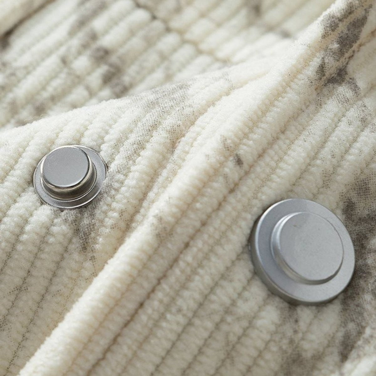 Macro shot of silver popper buttons on ribbed corduroy jacket fabric