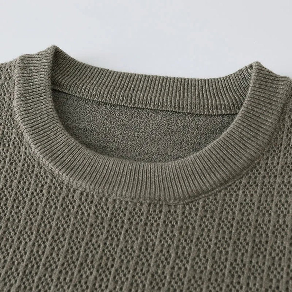 Detailed view of ribbed crew neckline on khaki knitted jumper