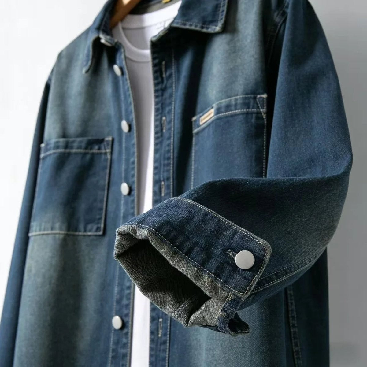 Close-up of rolled cuff and press-stud fastening on dark wash denim shirt