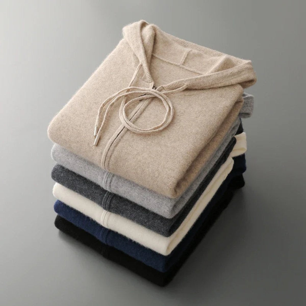 Stack of folded cashmere zip hoodies in beige, grey, navy and black shades