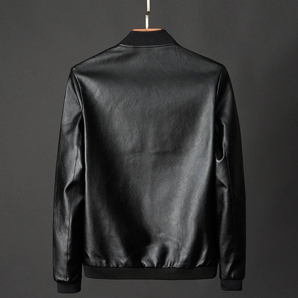 Rear view of black faux leather bomber jacket on hanger