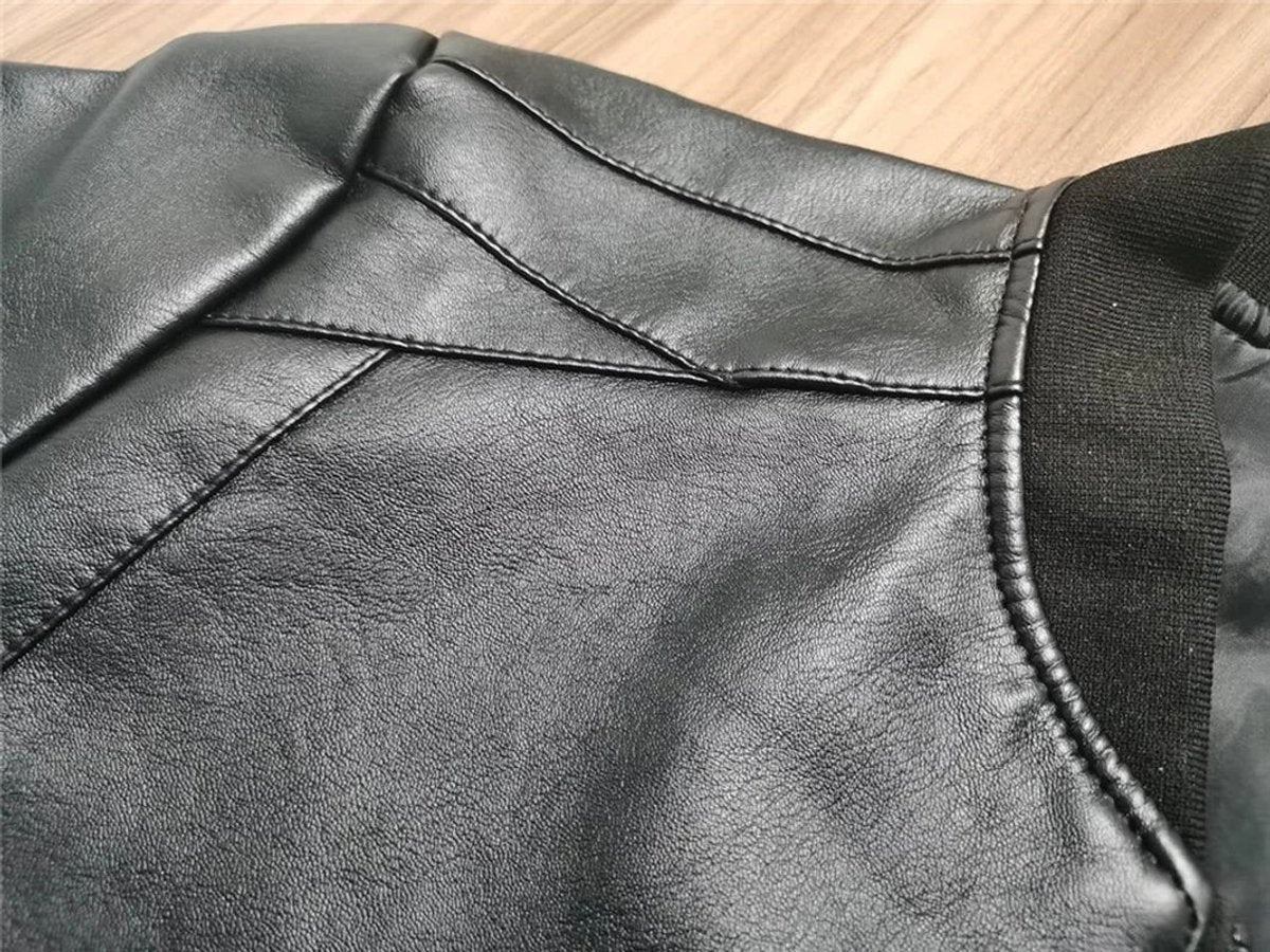 Close-up of black faux leather bomber jacket showing stitched seam detail