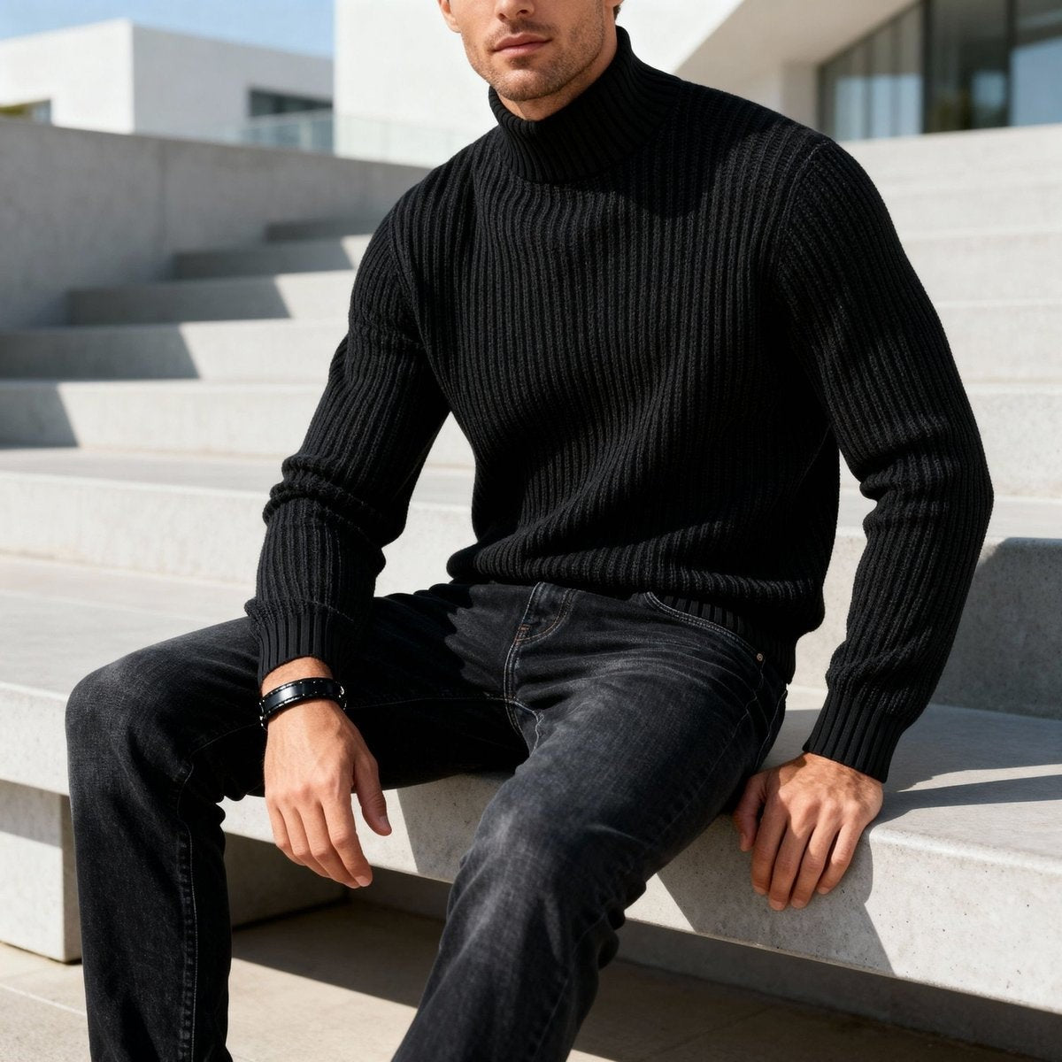 Black heavyweight ribbed jumper worn with grey jeans on stone steps